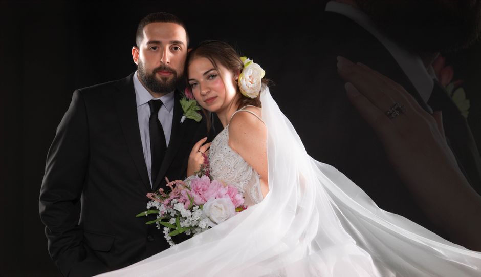Romantic wedding portrait of a couple with a floral bouquet and elegant attire.