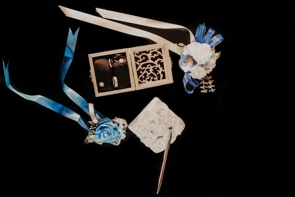 A beautiful top view of wedding rings in a decorative box surrounded by floral elements and ribbons.