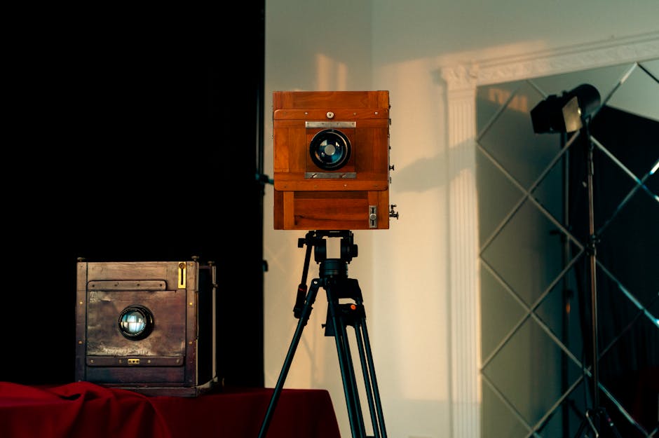 A vintage wooden large format camera on a tripod in an indoor studio setting.