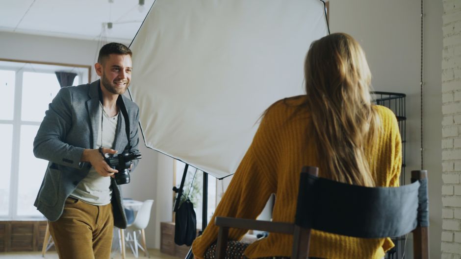 Photographer capturing a model indoors with lighting setup, creating professional portraits.