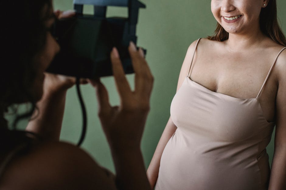 A woman smiles in a studio while being photographed with an instant camera.