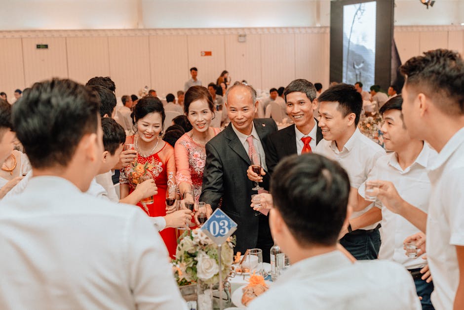A joyous gathering at a wedding reception with people toasting and smiling indoors.