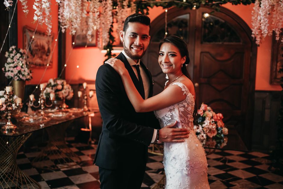 A joyful wedding couple smiling and embracing at an elegant indoor venue.