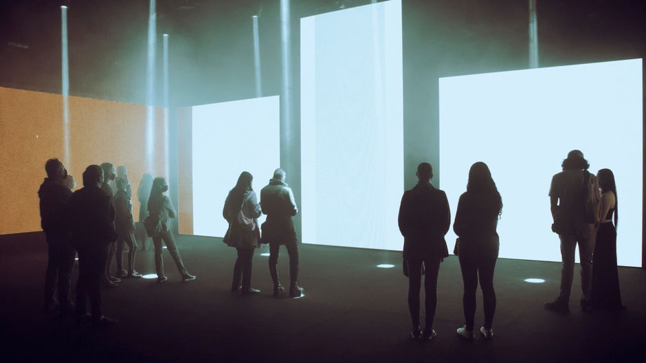 Visitors exploring an immersive digital art exhibition with large illuminated screens.